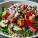 The wholesome quinoa warm salad bowl is topped with crumbled feta cheese and toasted pumpkin seeds for a nourishing meal.