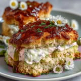Warm, flaky scones sweetened with dandelion honey, served with a generous dollop of clotted cream for an indulgent British tea-time treat.