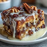 Layers of Easy Capirotada with Cinnamon, Piloncillo, and Raisins baked to golden perfection, topped with raisins, cheese, and a drizzle of rich cinnamon-spiced syrup.