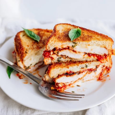 Golden-brown Chicken Parm Grilled Cheese sandwich oozing melted mozzarella, served with marinara dip.