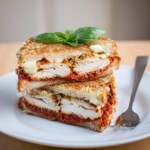 Close-up of crispy Chicken Parm Grilled Cheese on sourdough, highlighting crunchy panko and fresh basil.