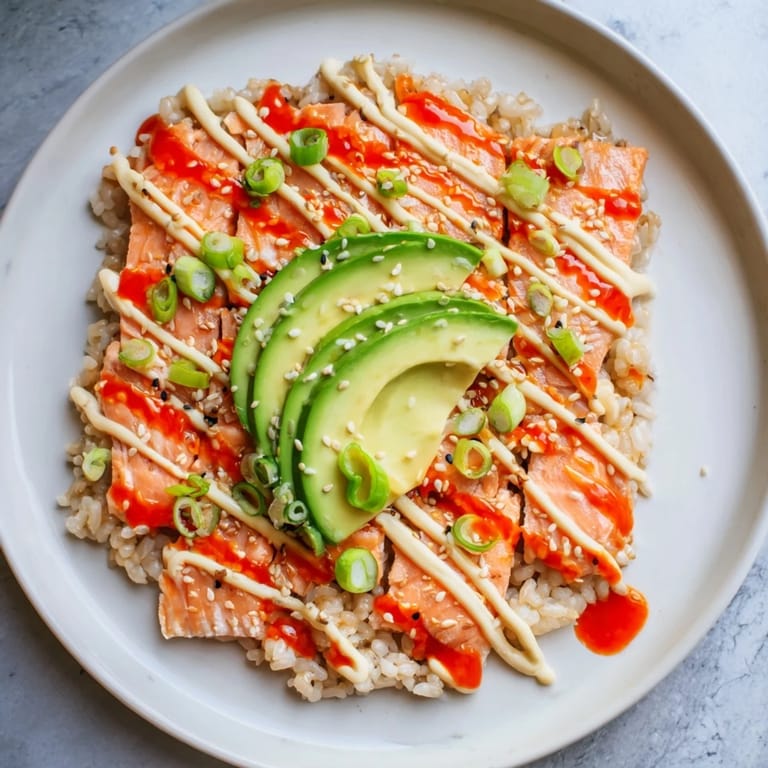 Close-up of the beautiful Emily Mariko Salmon Rice Bowl: creamy avocado and toasted sesame seeds sparkle.