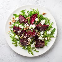Roasted beet goat cheese salad with vibrant red beets, creamy crumbled cheese, and toasted walnuts on fresh arugula.